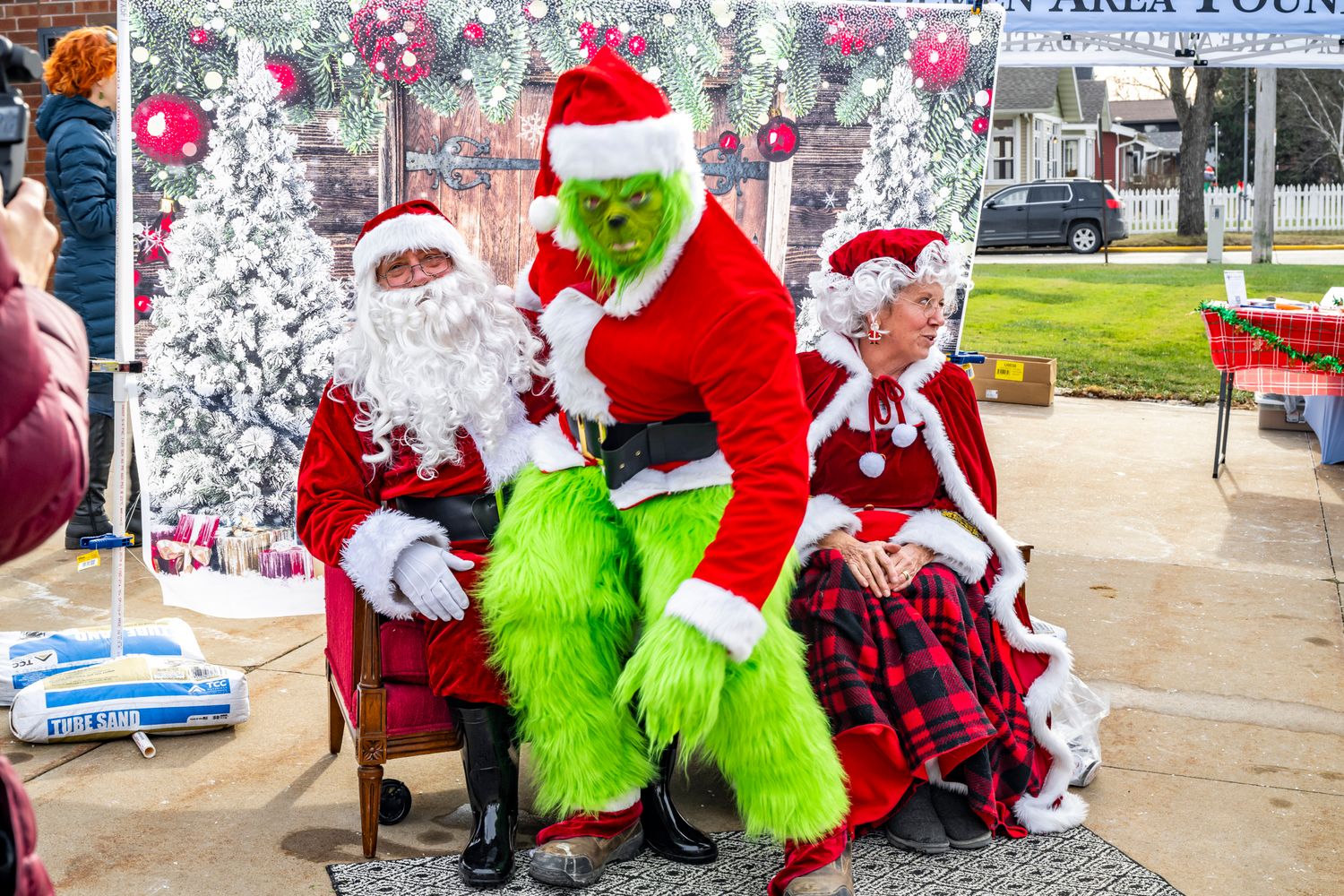 Holiday scene with Santa Claus and the Grinch character posing together near Christmas decorations.