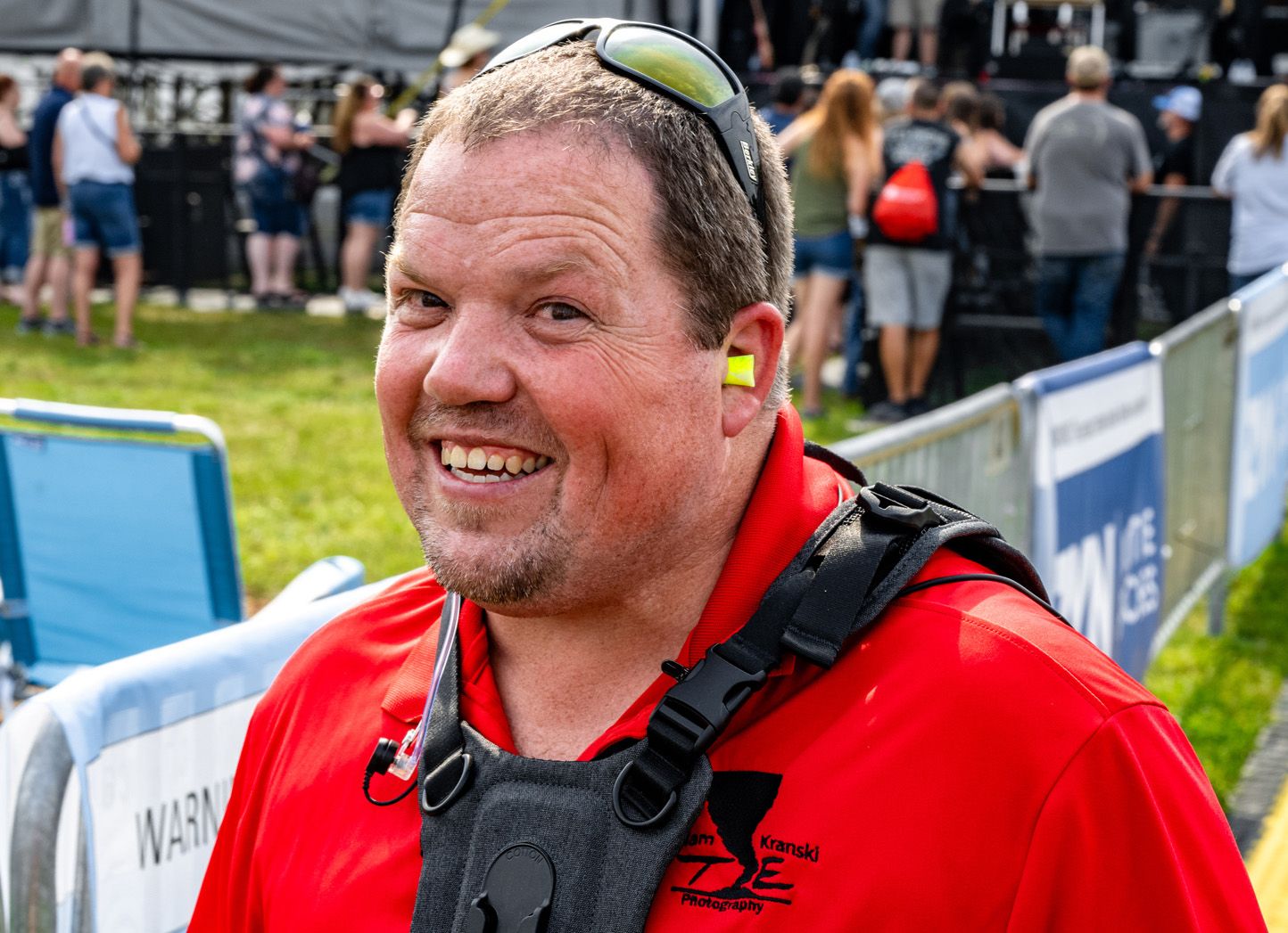 A person in a red safety vest and helmet smiles while participating in an outdoor adventure activity.