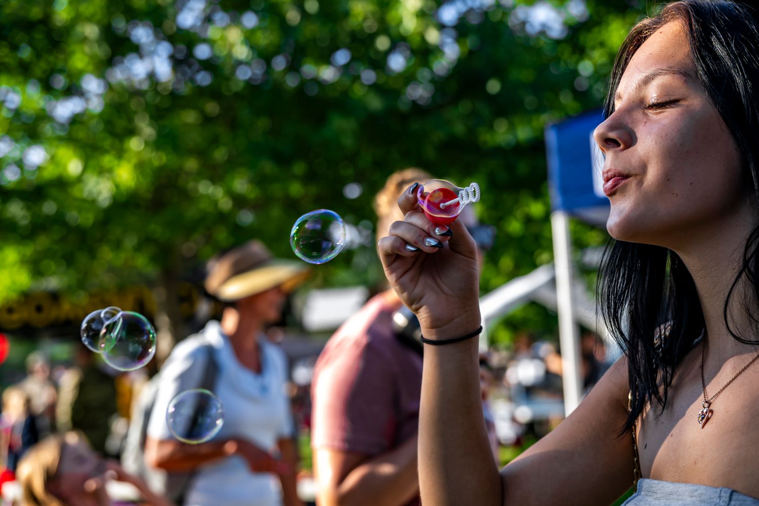 People blowing bubbles outdoors during a summer community celebration.