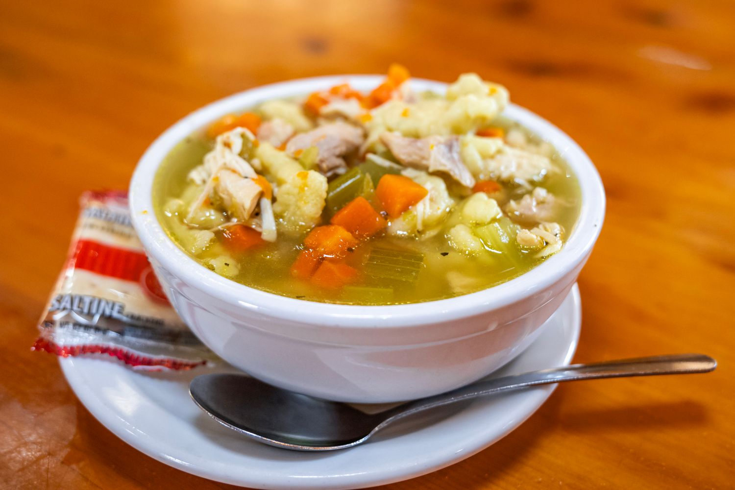Bowl of homemade chicken noodle soup with vegetables in clear broth.