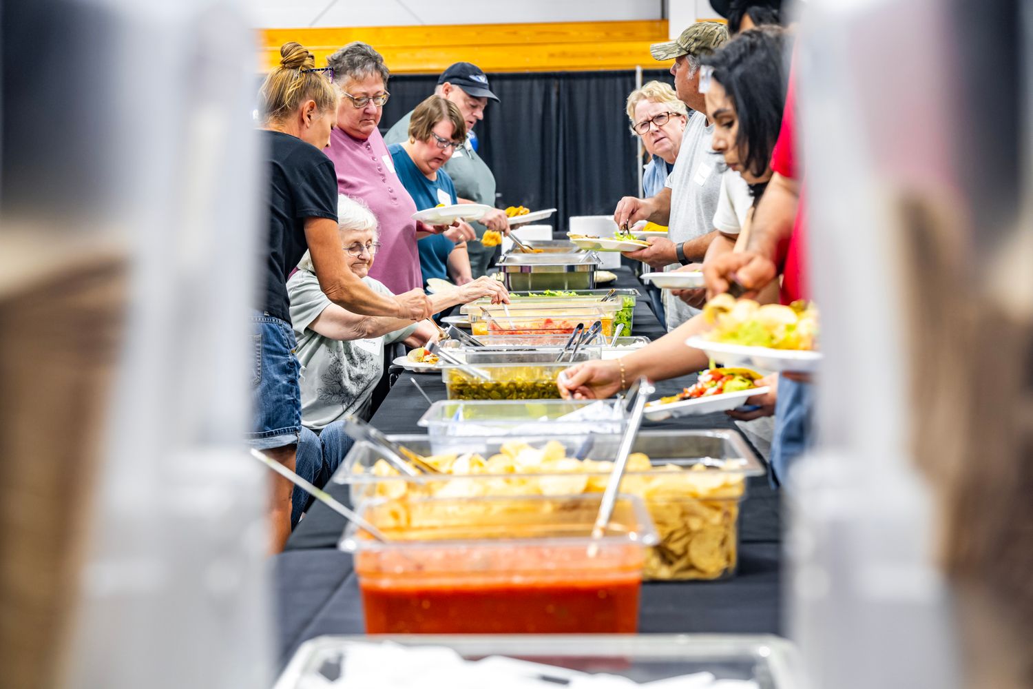 People gathered at tables participating in a community event with colorful decorations and supplies.