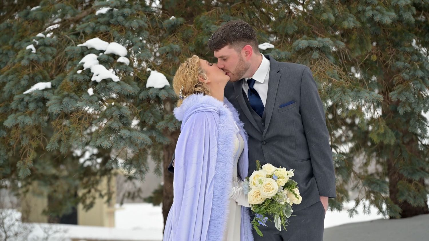 Romantic winter wedding scene with snow-covered evergreen trees in the background.