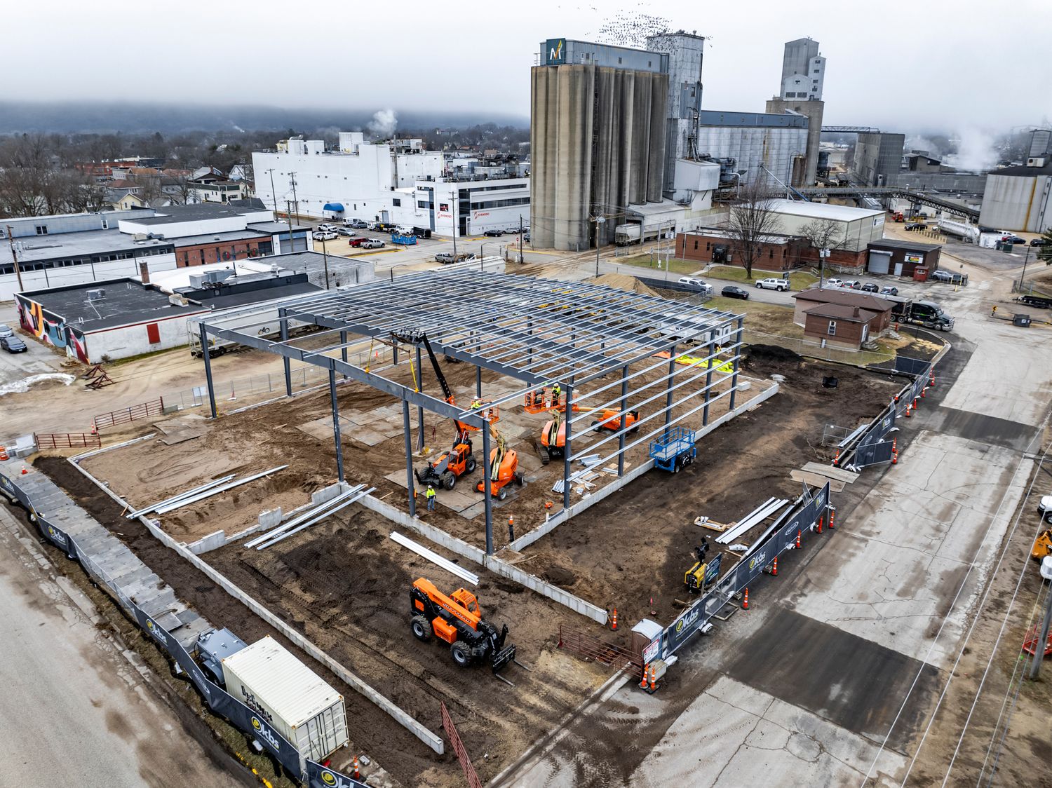 Industrial construction site with steel framework and cranes visible from above.