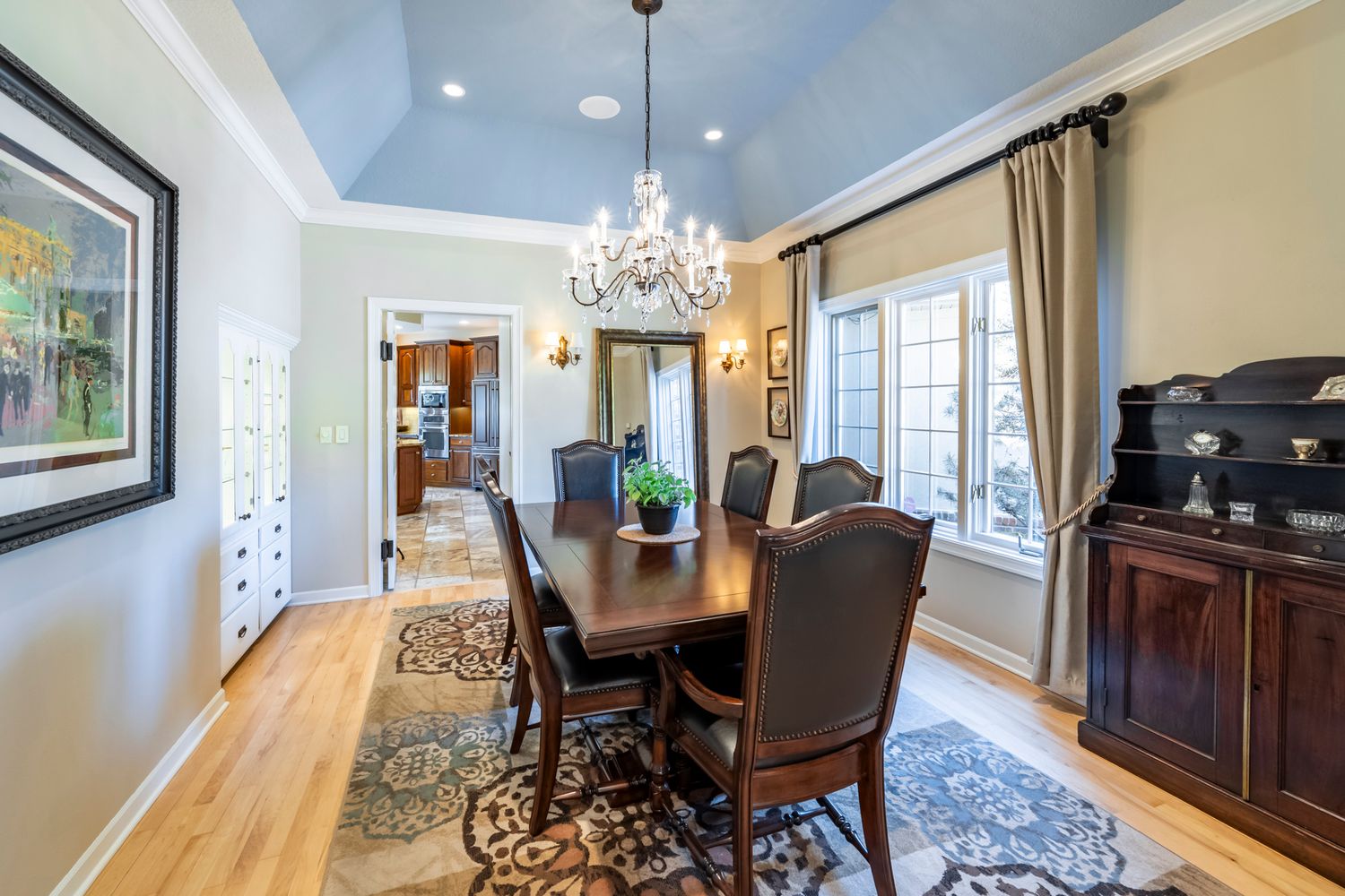 Elegant dining room with vaulted ceiling, crystal chandelier, and large windows.