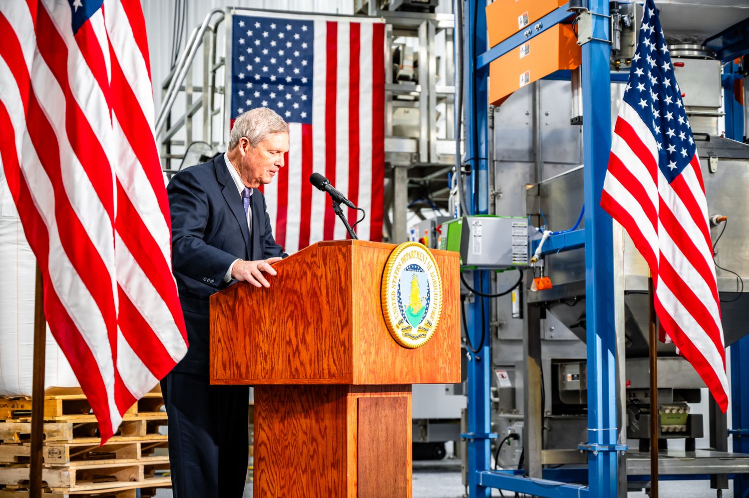 Political or business event venue with American flags and wooden podium setup.