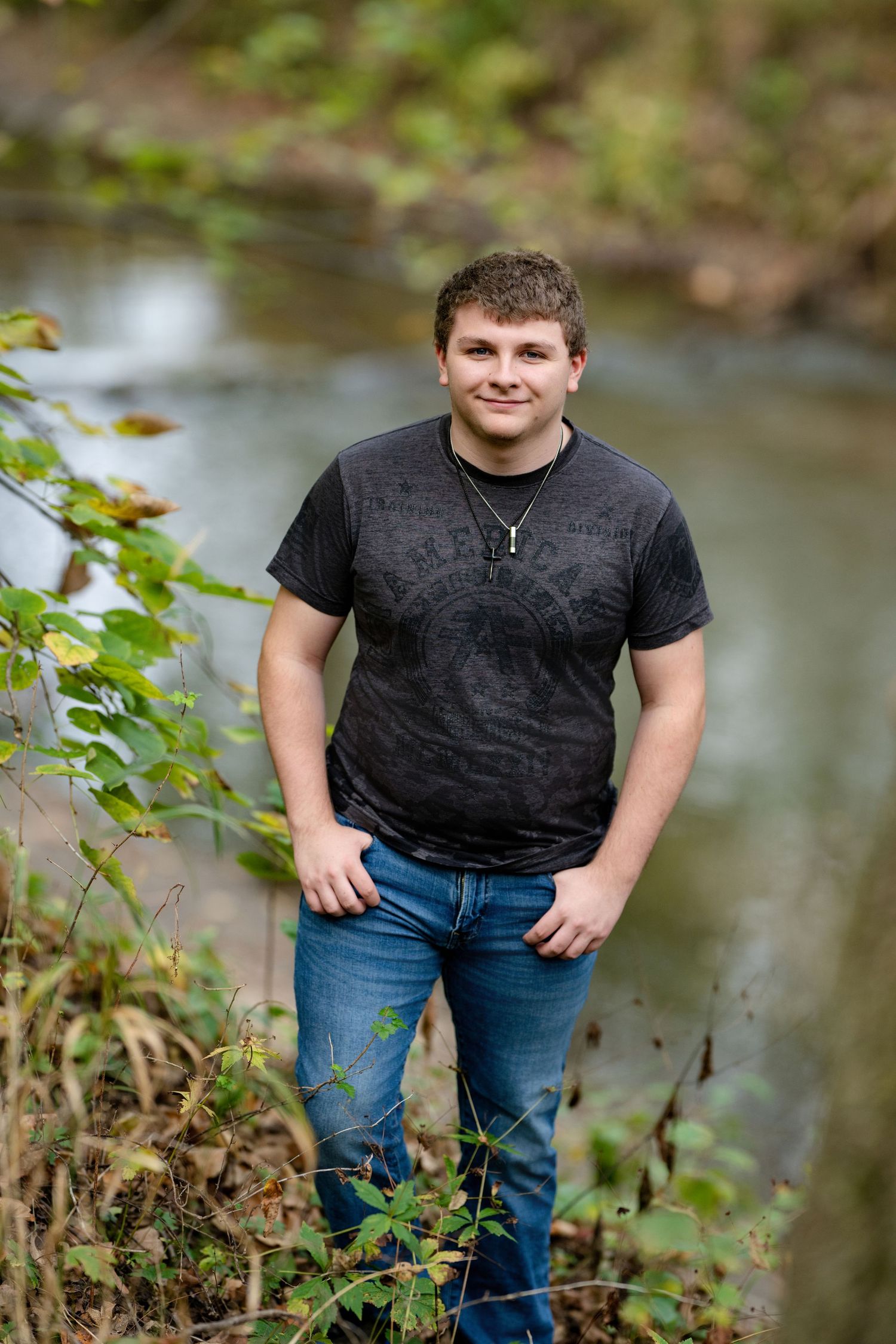 Casual portrait by creek wearing black t-shirt and jeans.