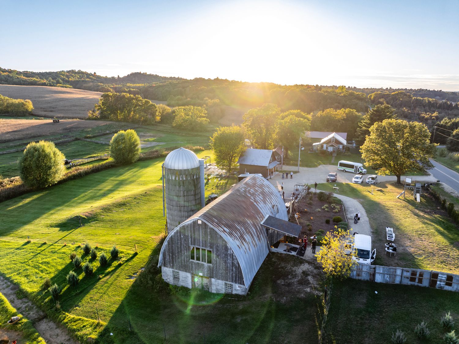 Sweeping aerial view of a countryside farm with rolling hills and agricultural buildings.