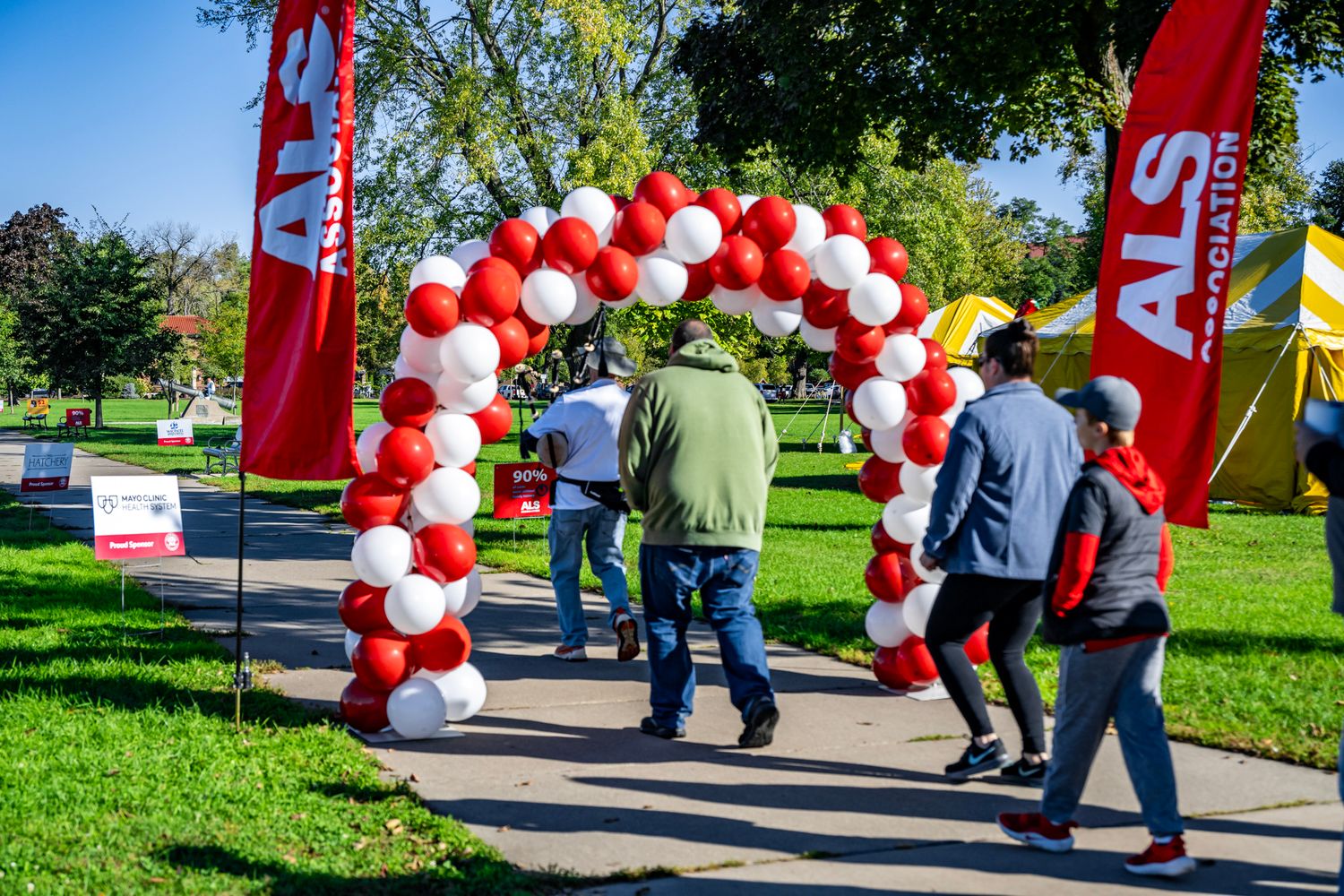 Red and white balloon decorations line walkway at outdoor community event.
