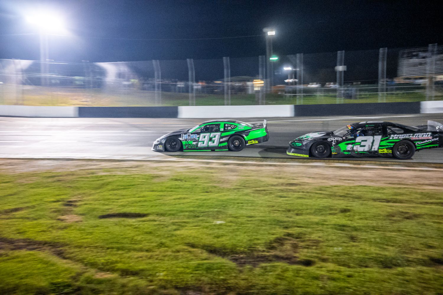 Multiple race cars compete on a professional racing circuit during daytime.
