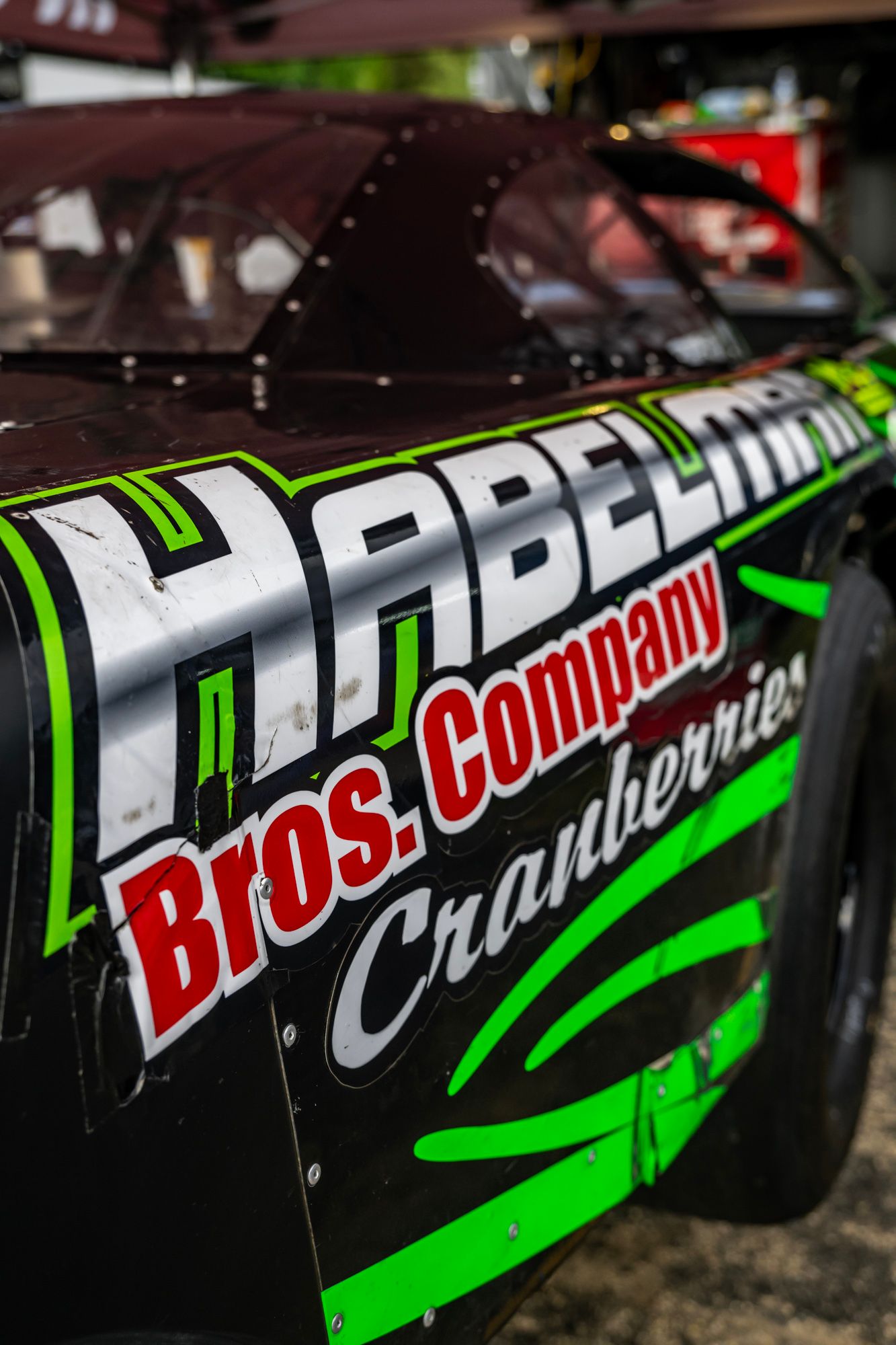 Detailed shot of racing graphics and sponsor logos on a black and green race car.