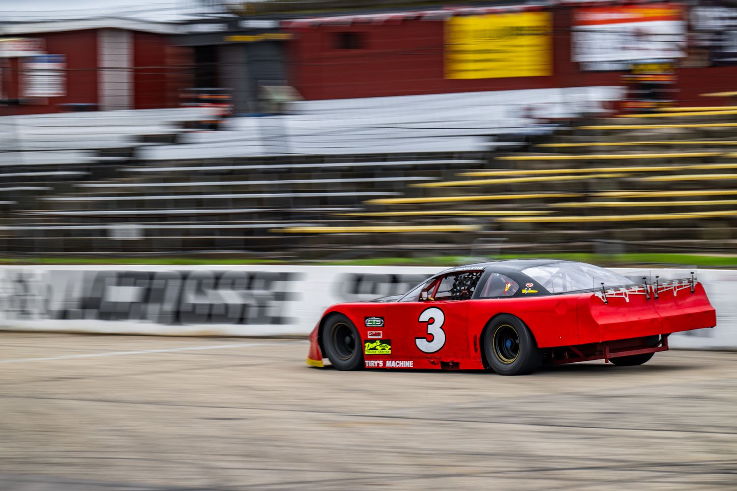 Racing cars speed past on track with motion blur effect.
