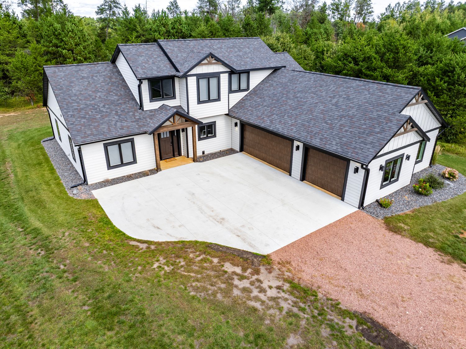 Modern white and black two-story house with attached garage viewed from above.