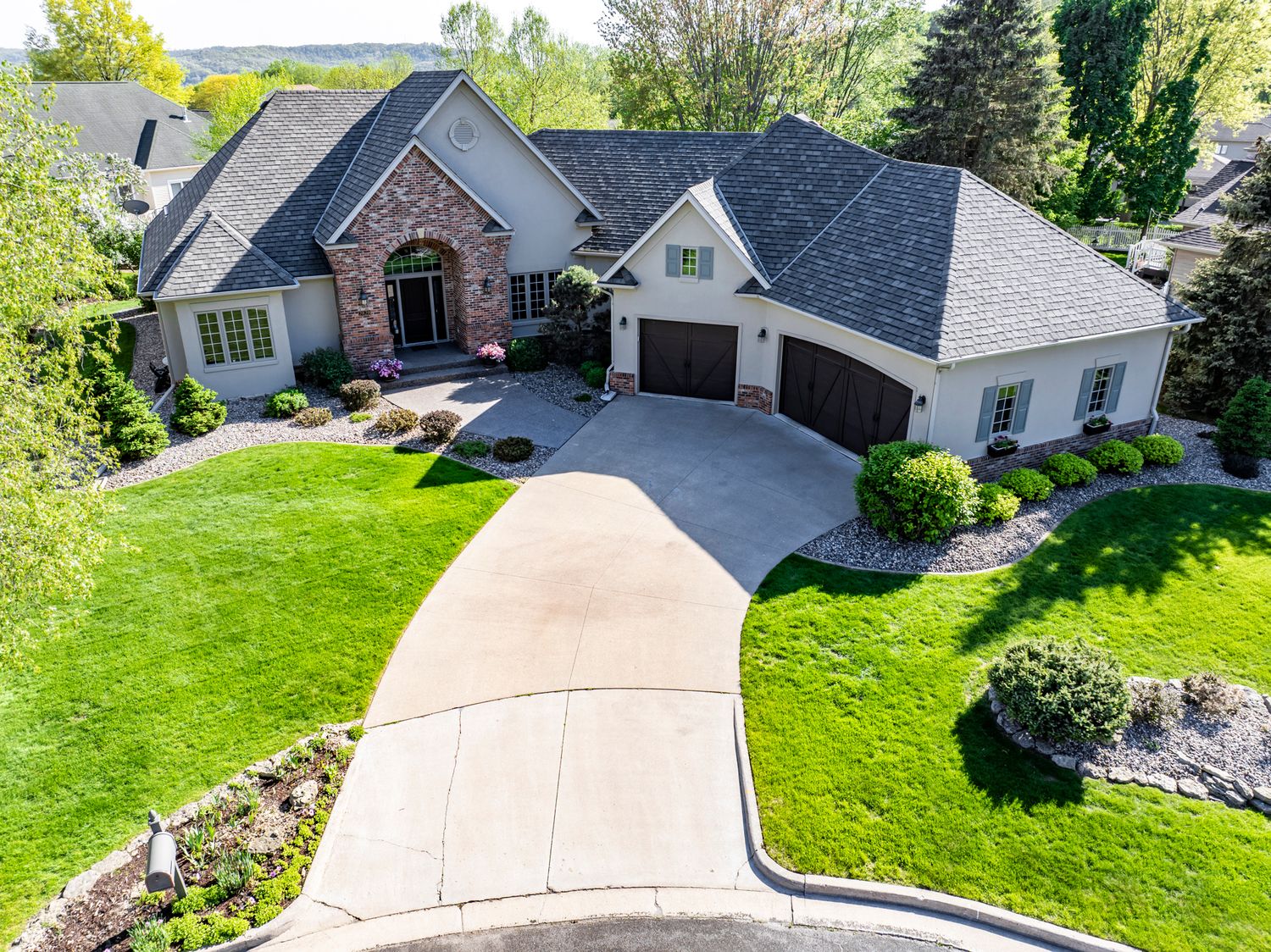 Panoramic aerial view of suburban home with manicured lawn and concrete driveway.