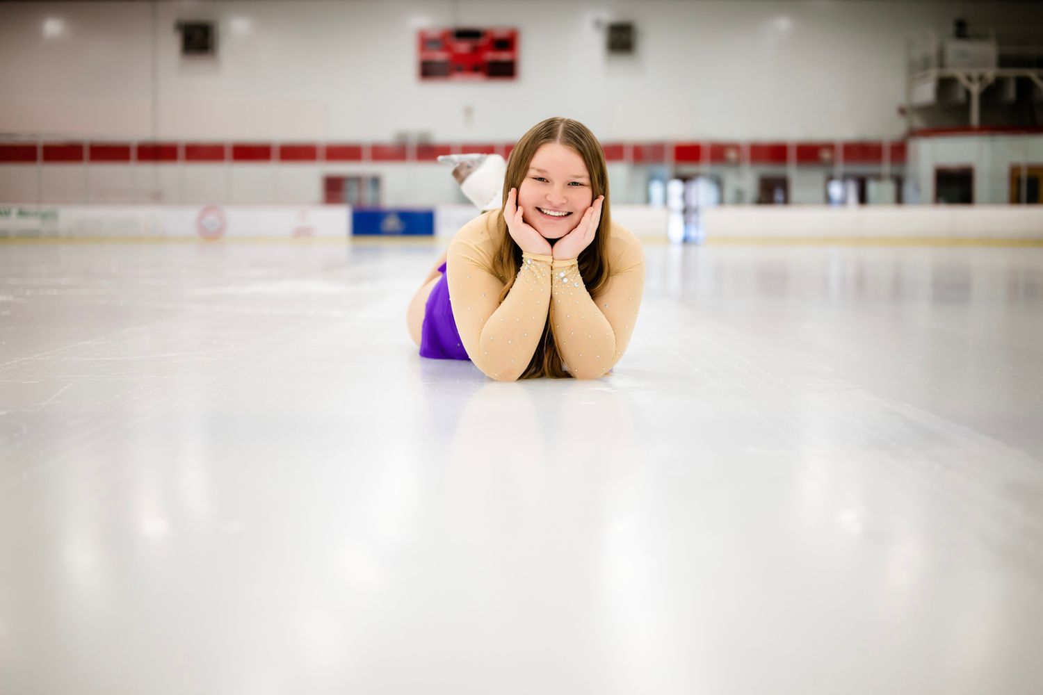 Figure skater in a sparkly purple costume performs gracefully on ice rink.