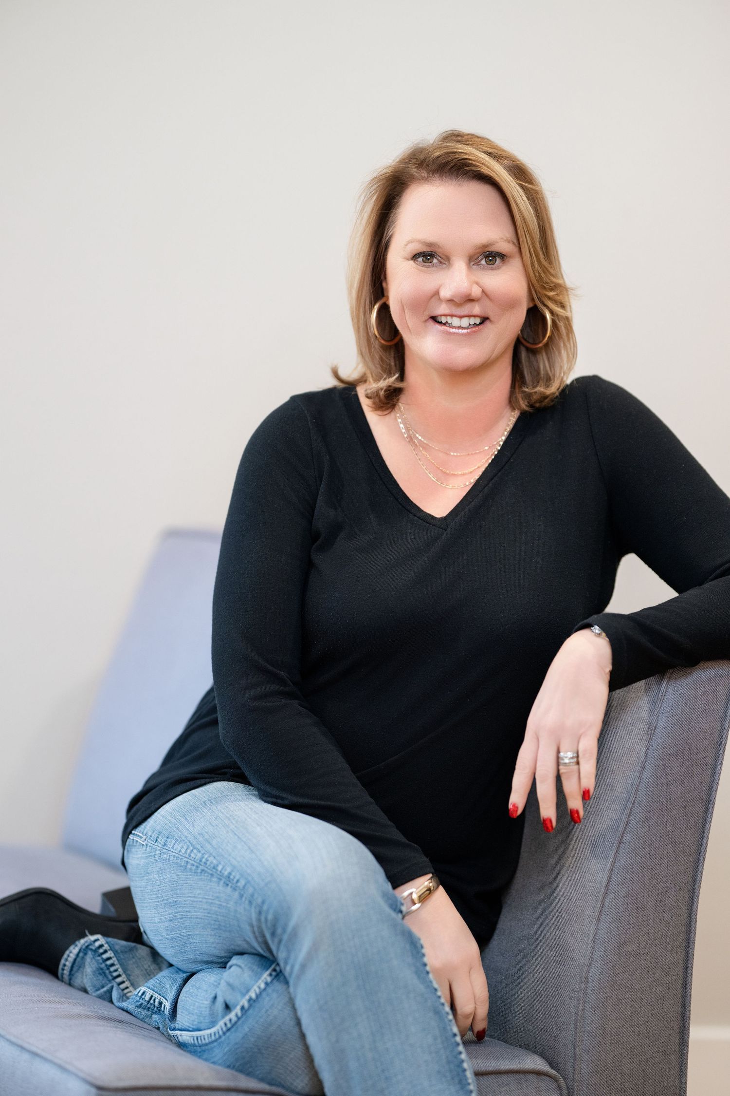 Portrait series showing a woman in black sweater and jeans posing casually on grey couch.