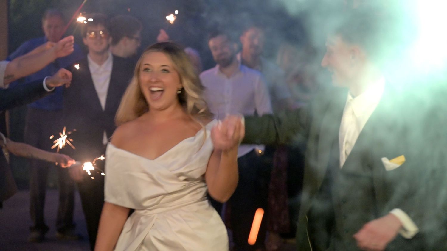 Celebration scene with sparklers and joyful moments at an evening wedding reception.