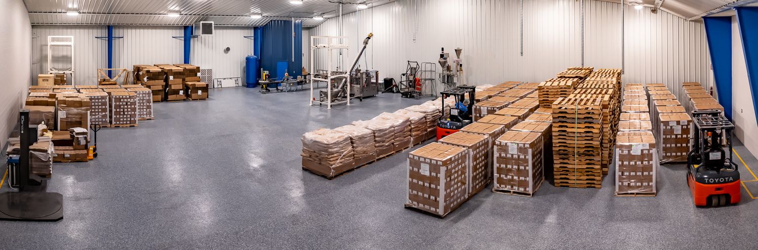 Panoramic view of a warehouse interior with stacked boxes and processing equipment.