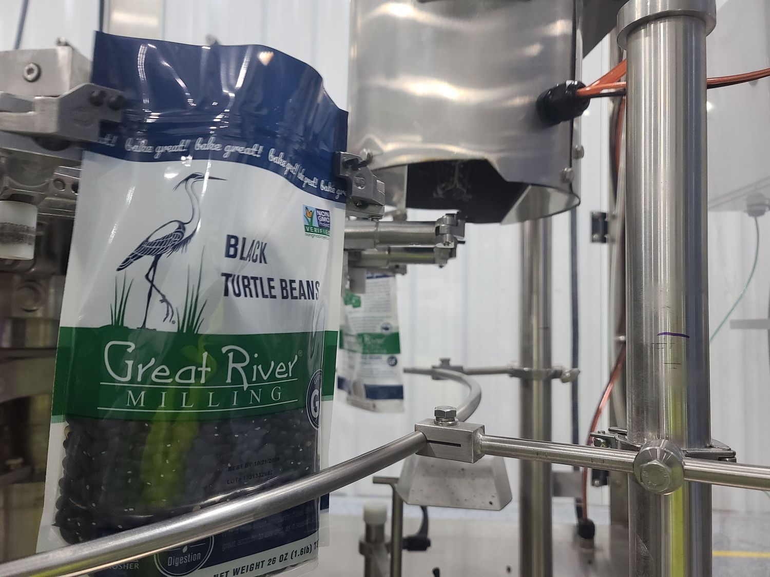 Manufacturing equipment with Great River Milling product packaging visible in processing facility.
