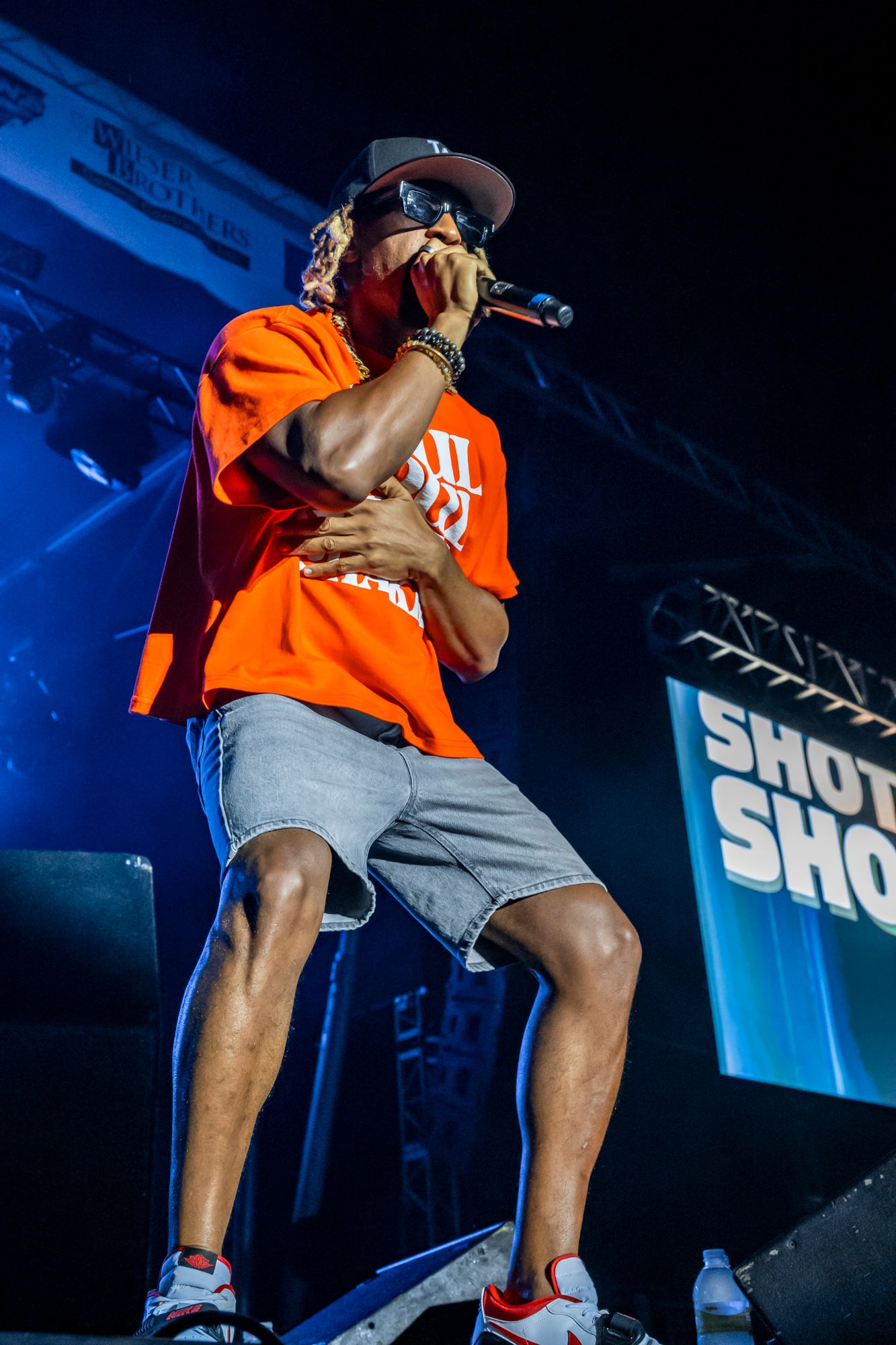 Performers in orange attire energetically moving on stage during a nighttime concert.