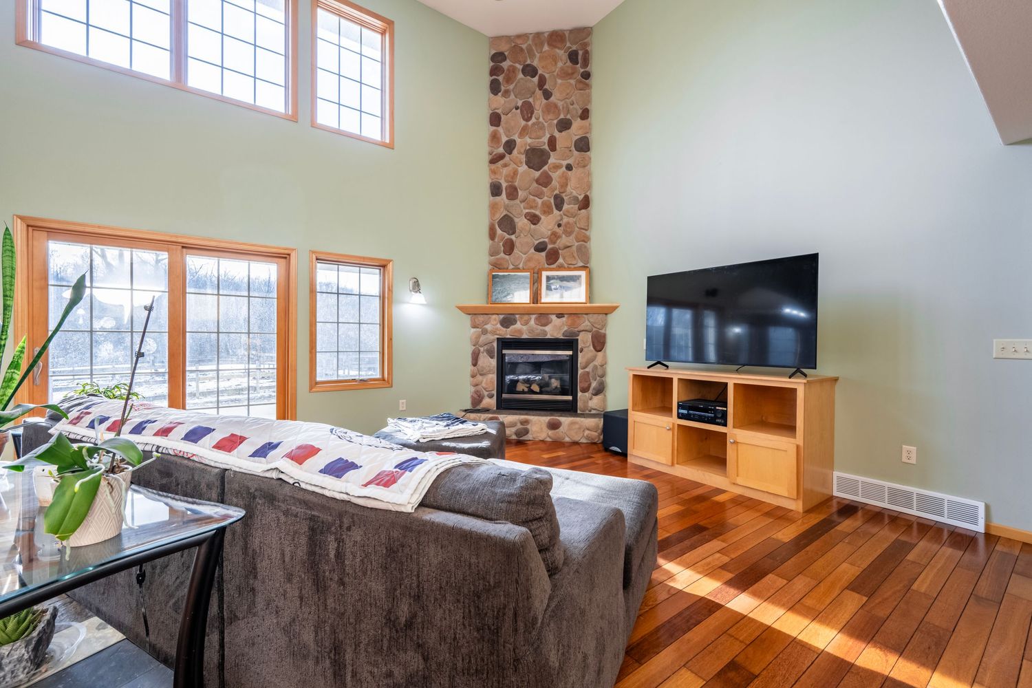 Bright living room interior with stone fireplace and large windows letting in natural light.