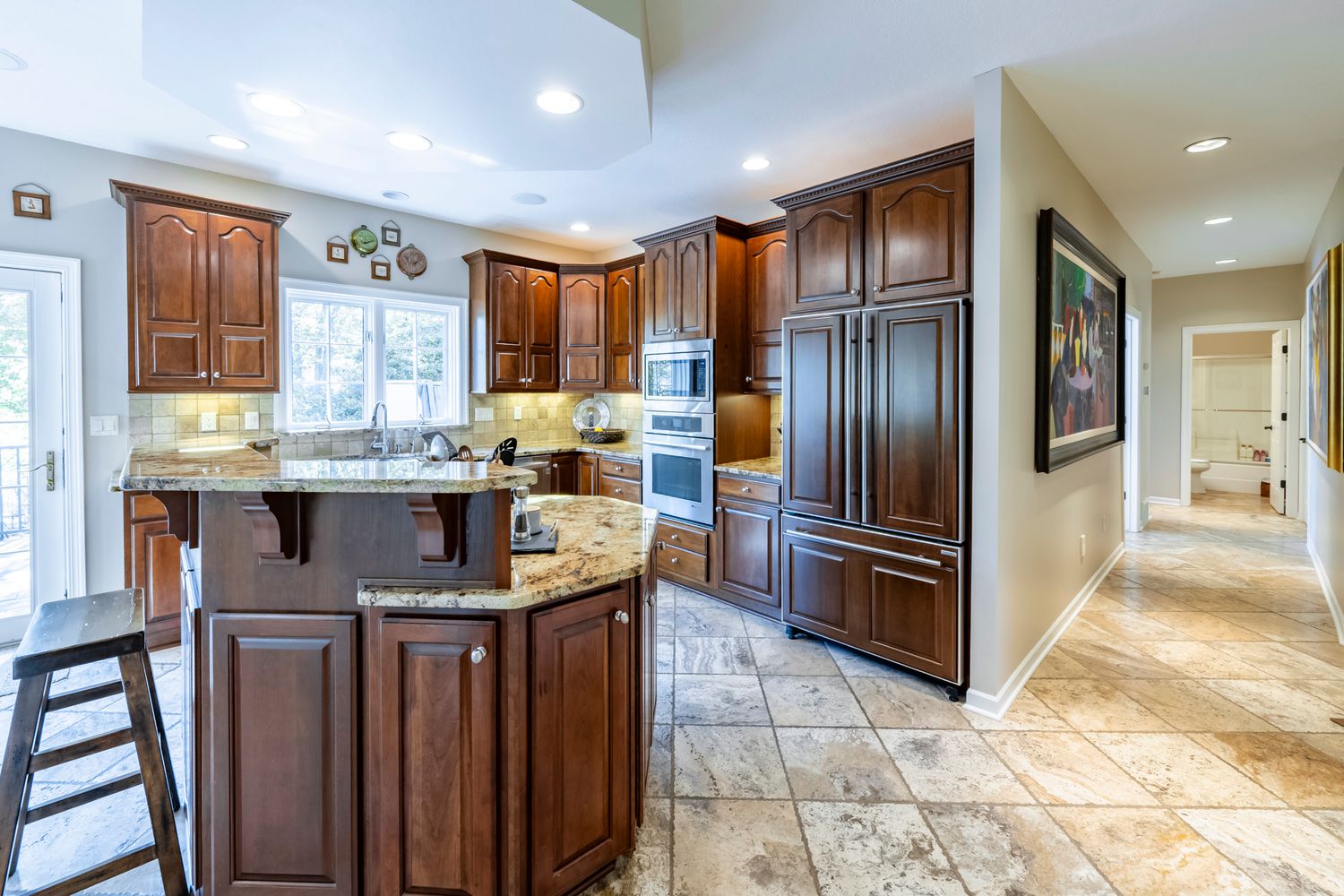 Long hallway with dark wood cabinetry and tile flooring leading to kitchen area.