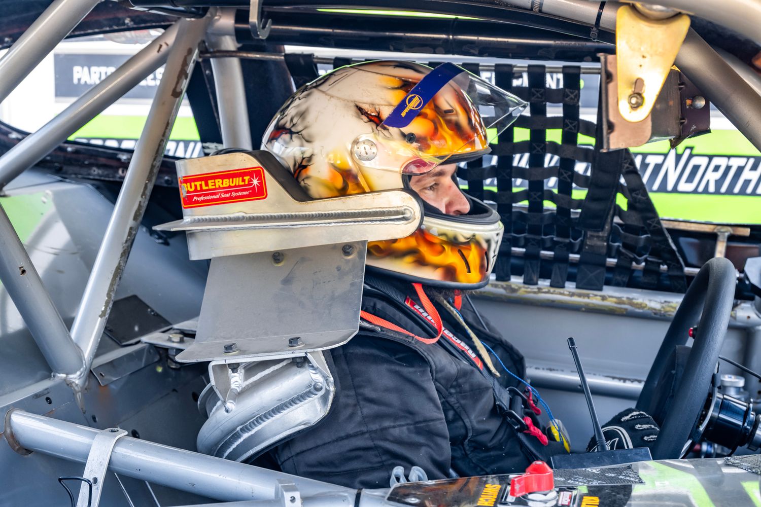 Interior view of race car cockpit showing steering wheel and dashboard instruments.