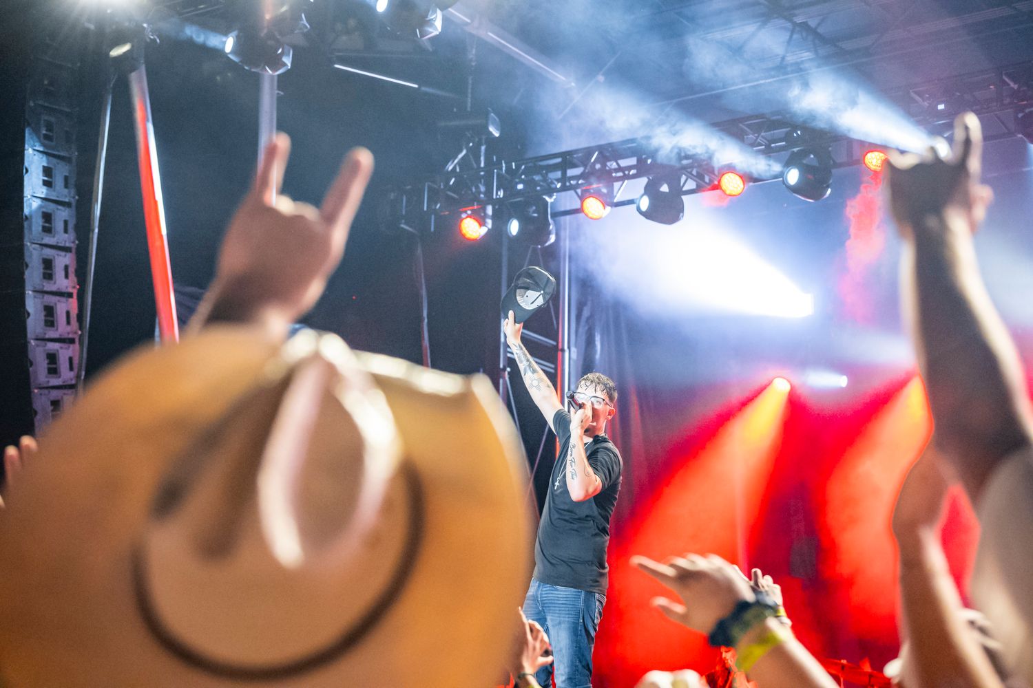 Crowd raising hands at a concert with bright stage lights creating a energetic atmosphere.