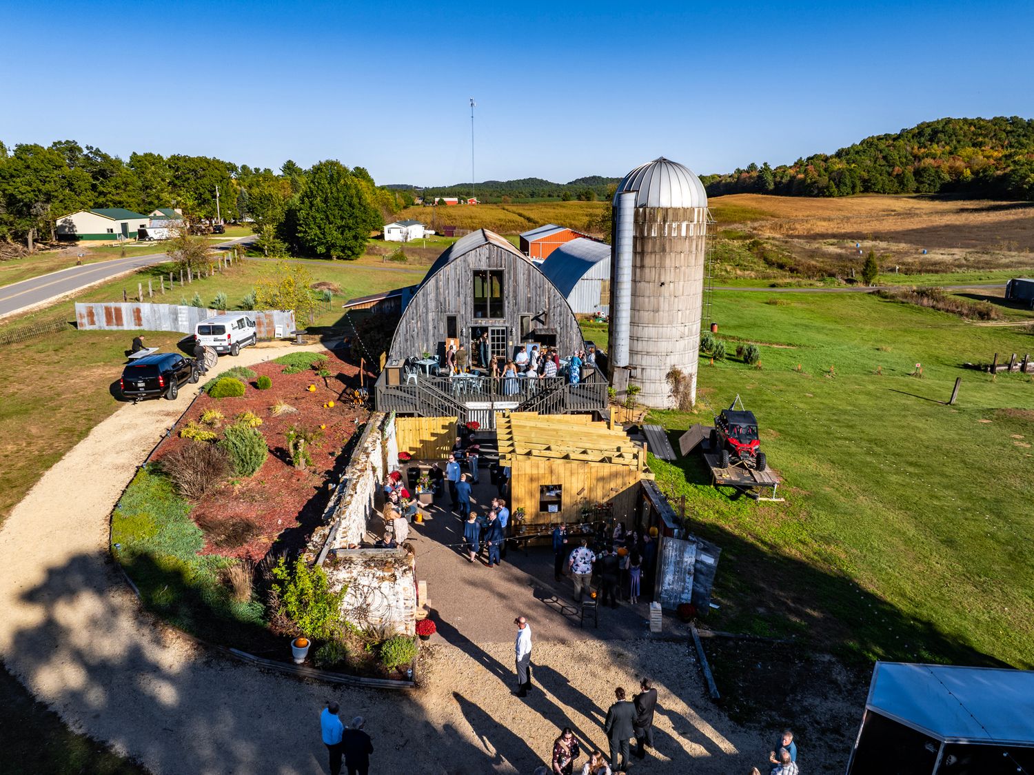 Panoramic aerial view of rural farmland with barns and silos at sunset.