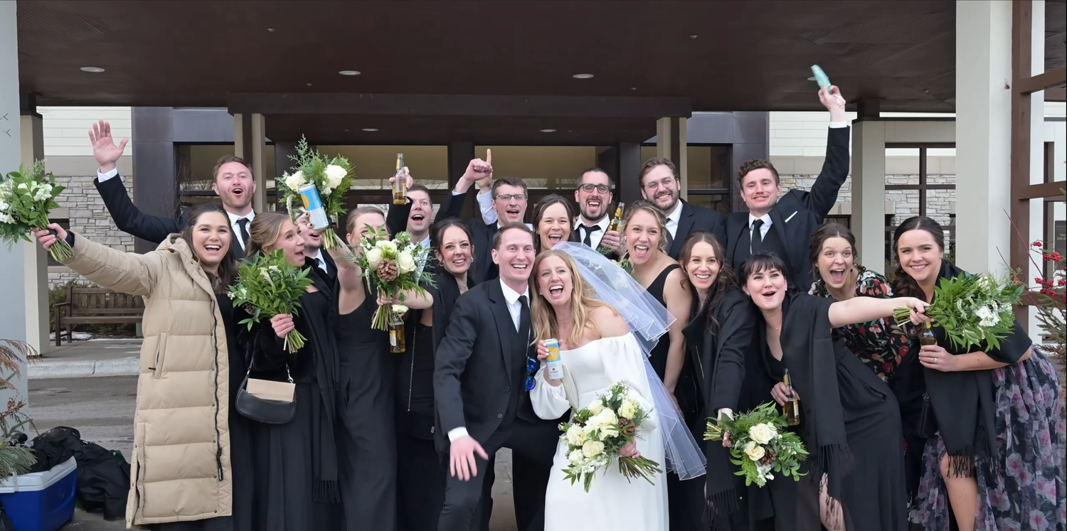 Large group photo of wedding guests standing together outside a venue.