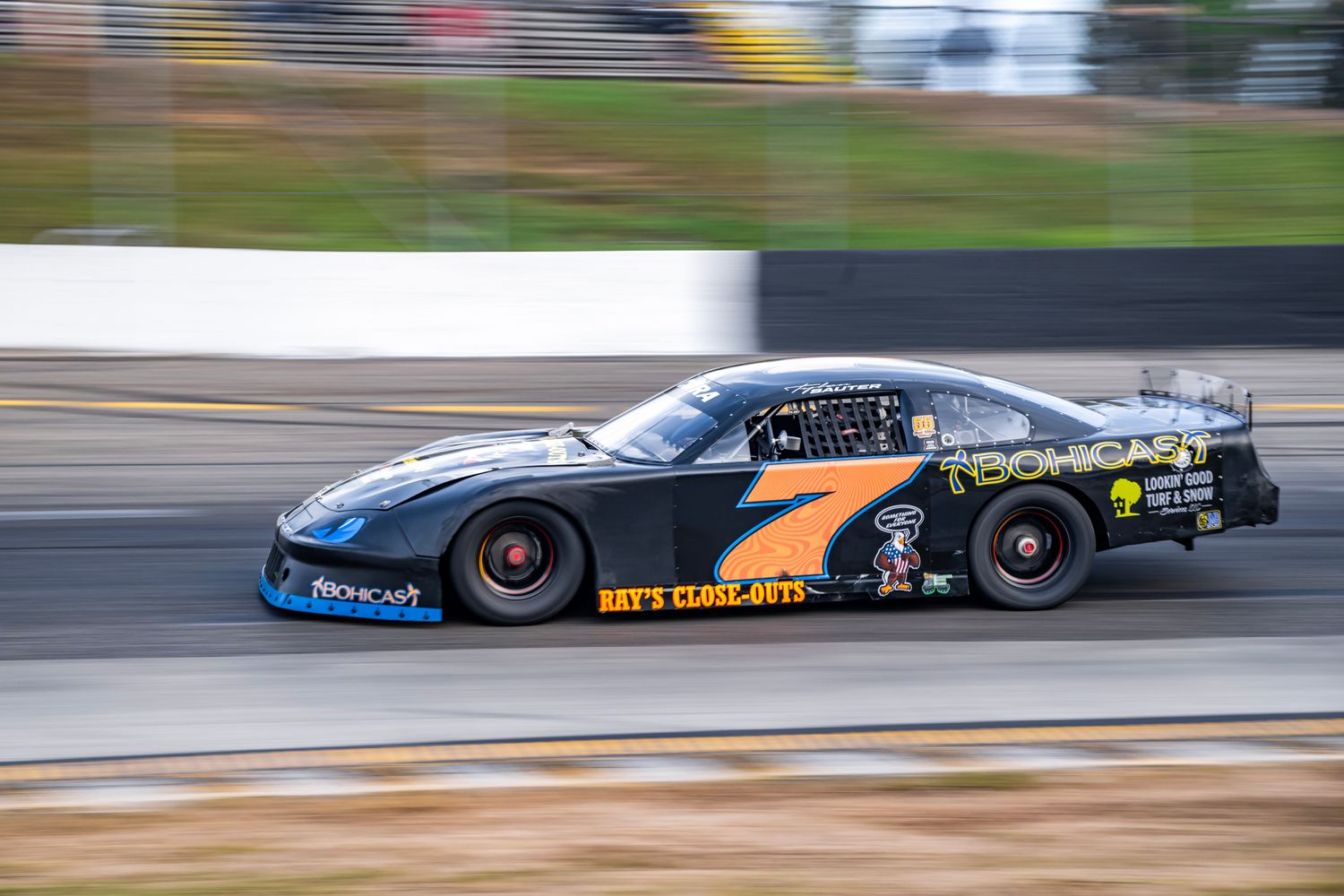 Black race cars in motion on racetrack with motion blur effect.