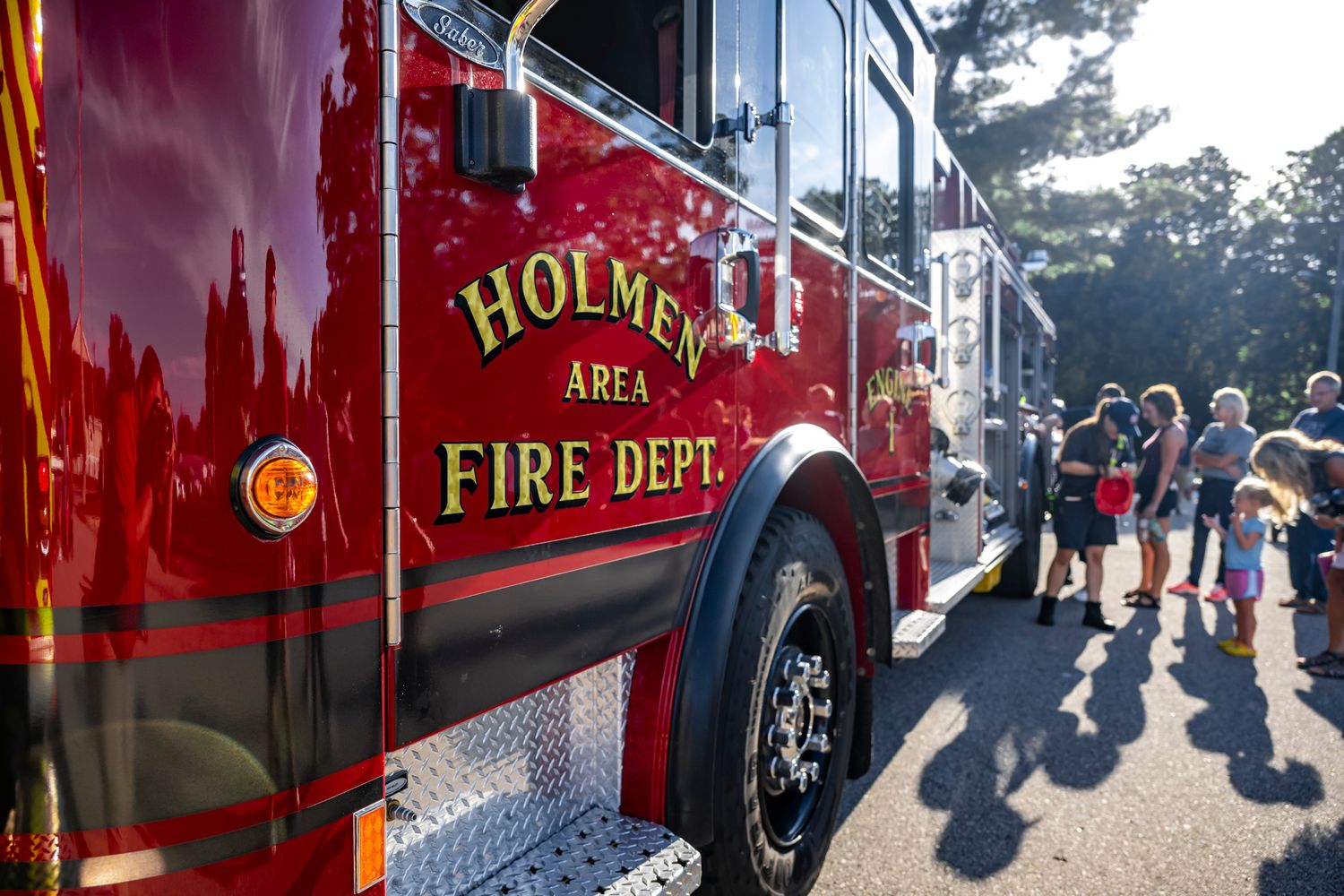 Line of red fire trucks parked at a community gathering.