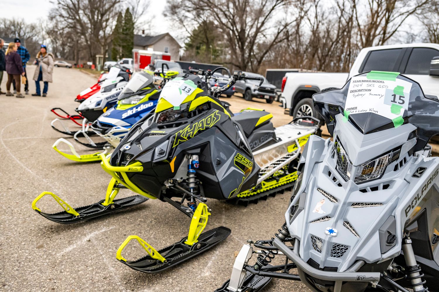 Row of parked snowmobiles on display at an outdoor winter event.