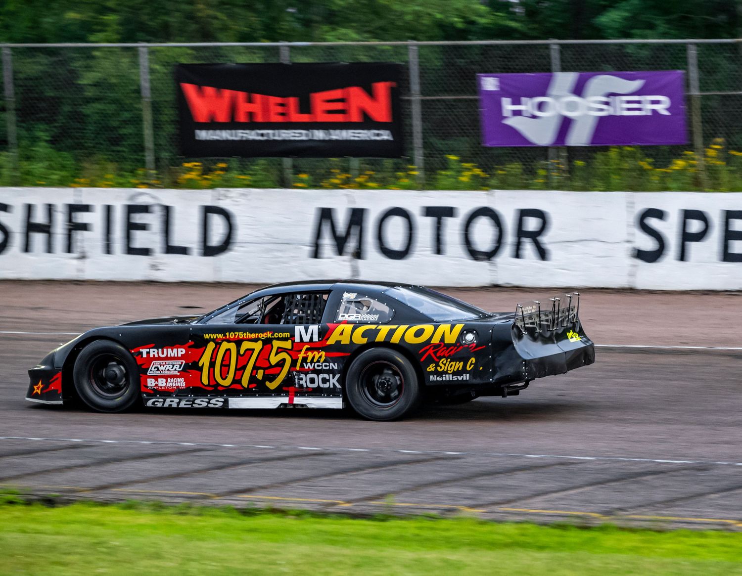 Stock cars racing on an oval track at Sheffield Motor Speedway with sponsor logos visible.