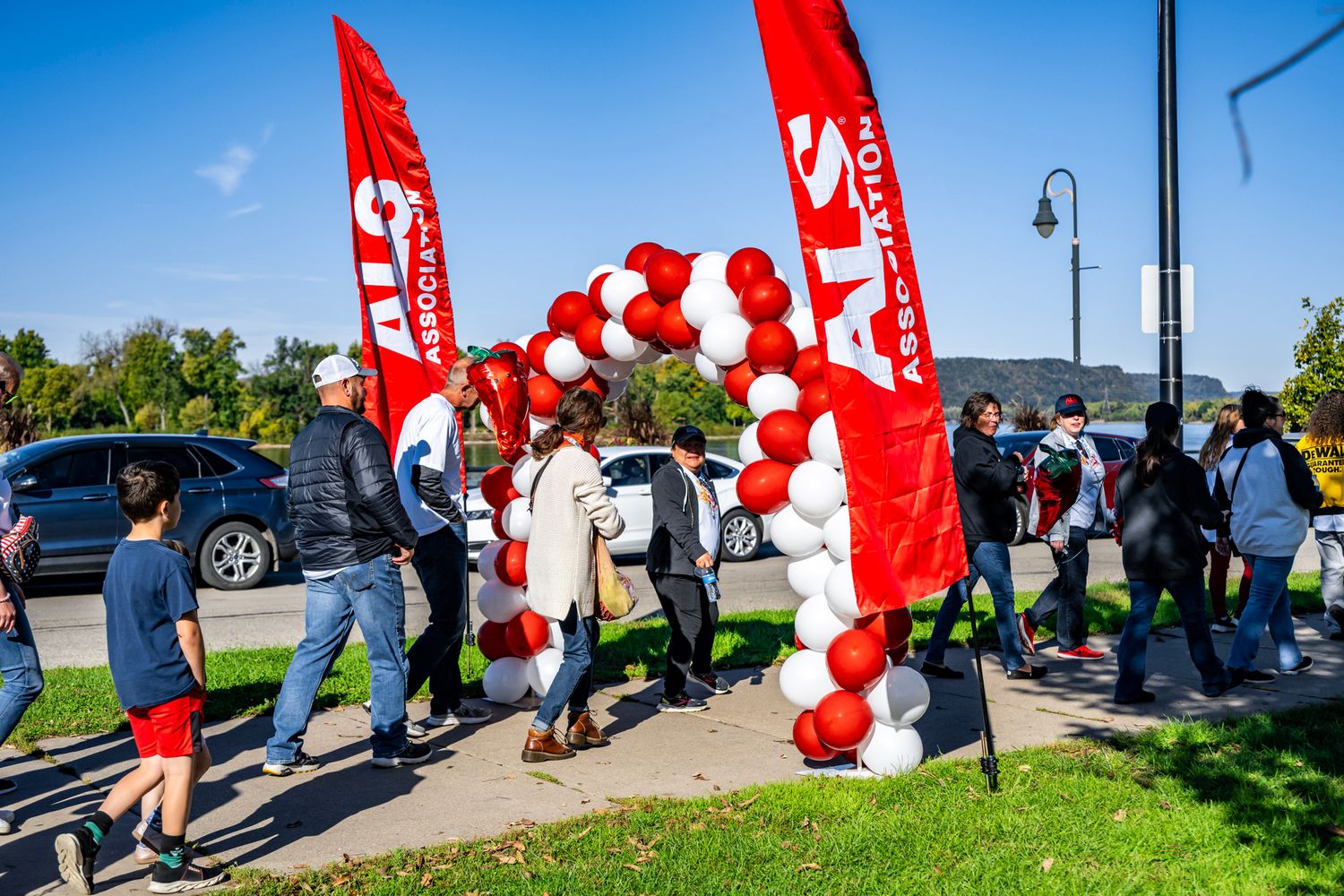 Red banners and balloon arches mark path at outdoor community gathering.
