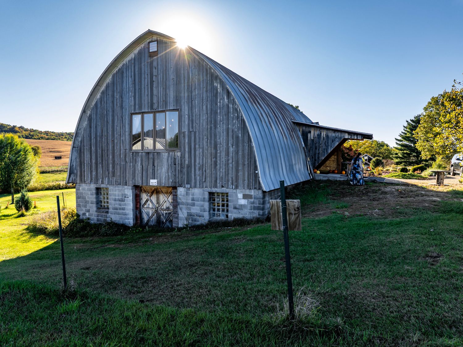 Wide panoramic shot of weathered barn structures in a rural landscape at dusk.