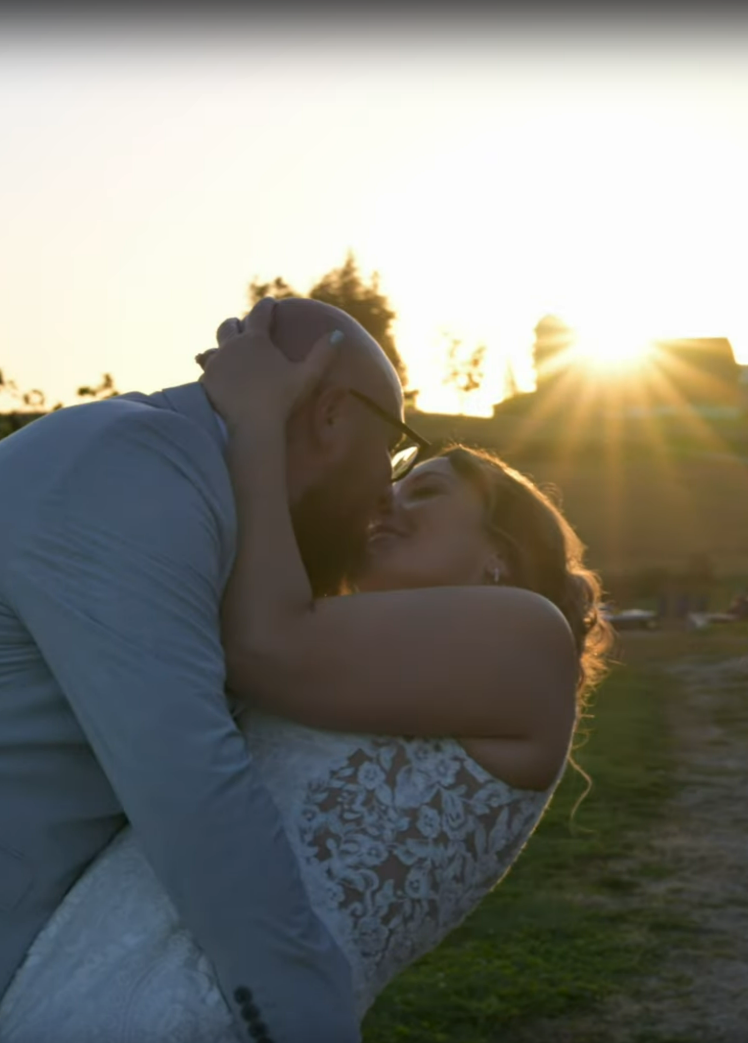 A romantic sunset silhouette of a couple embracing on their wedding day.