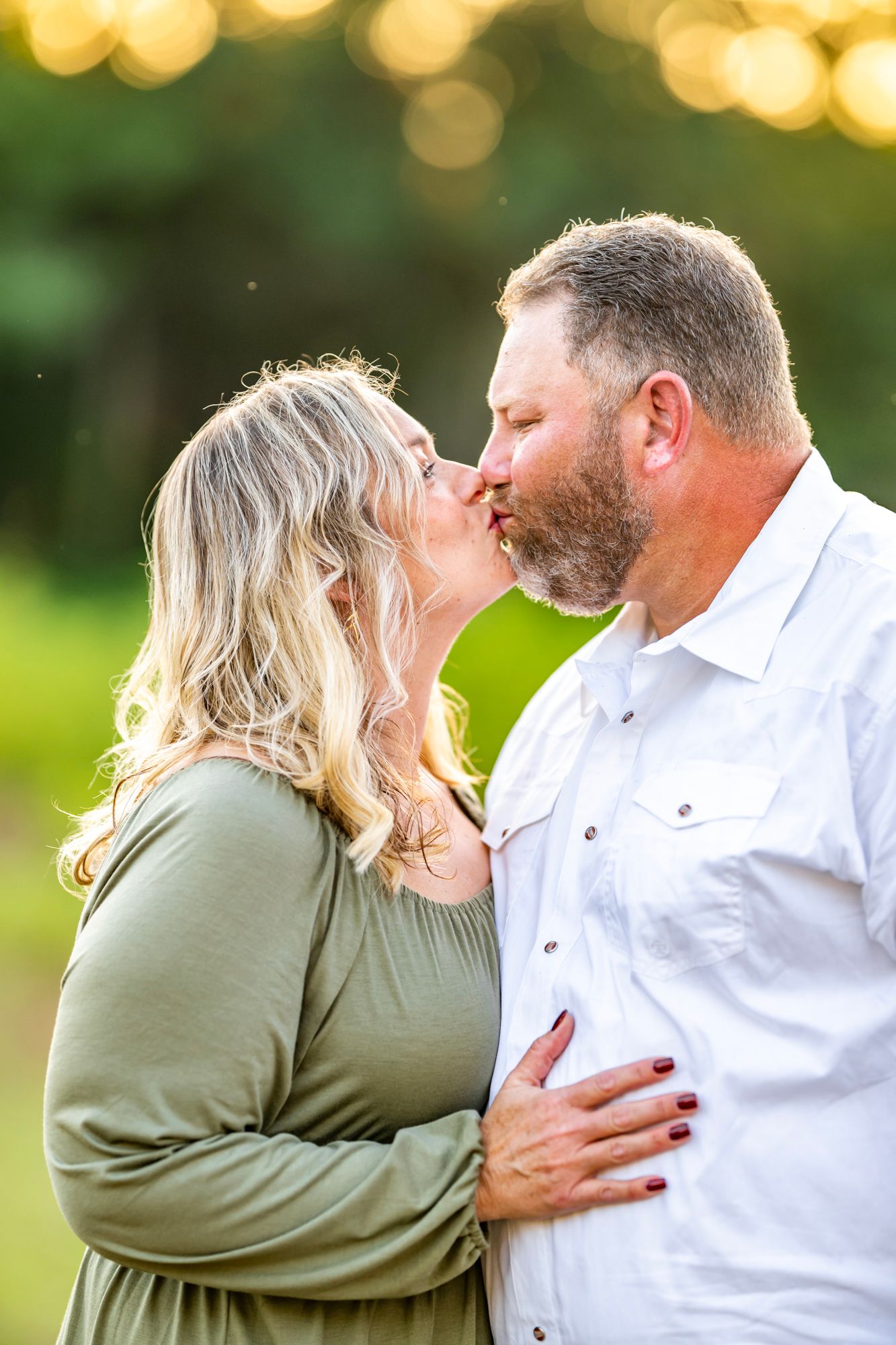 Romantic sunset photo session with couple embracing in a natural outdoor setting.