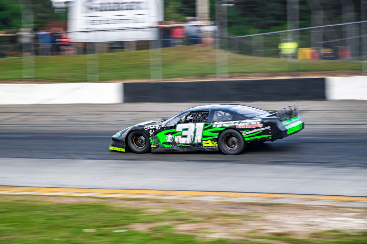 Race cars speed around a track during a competitive motorsport event at sunset.
