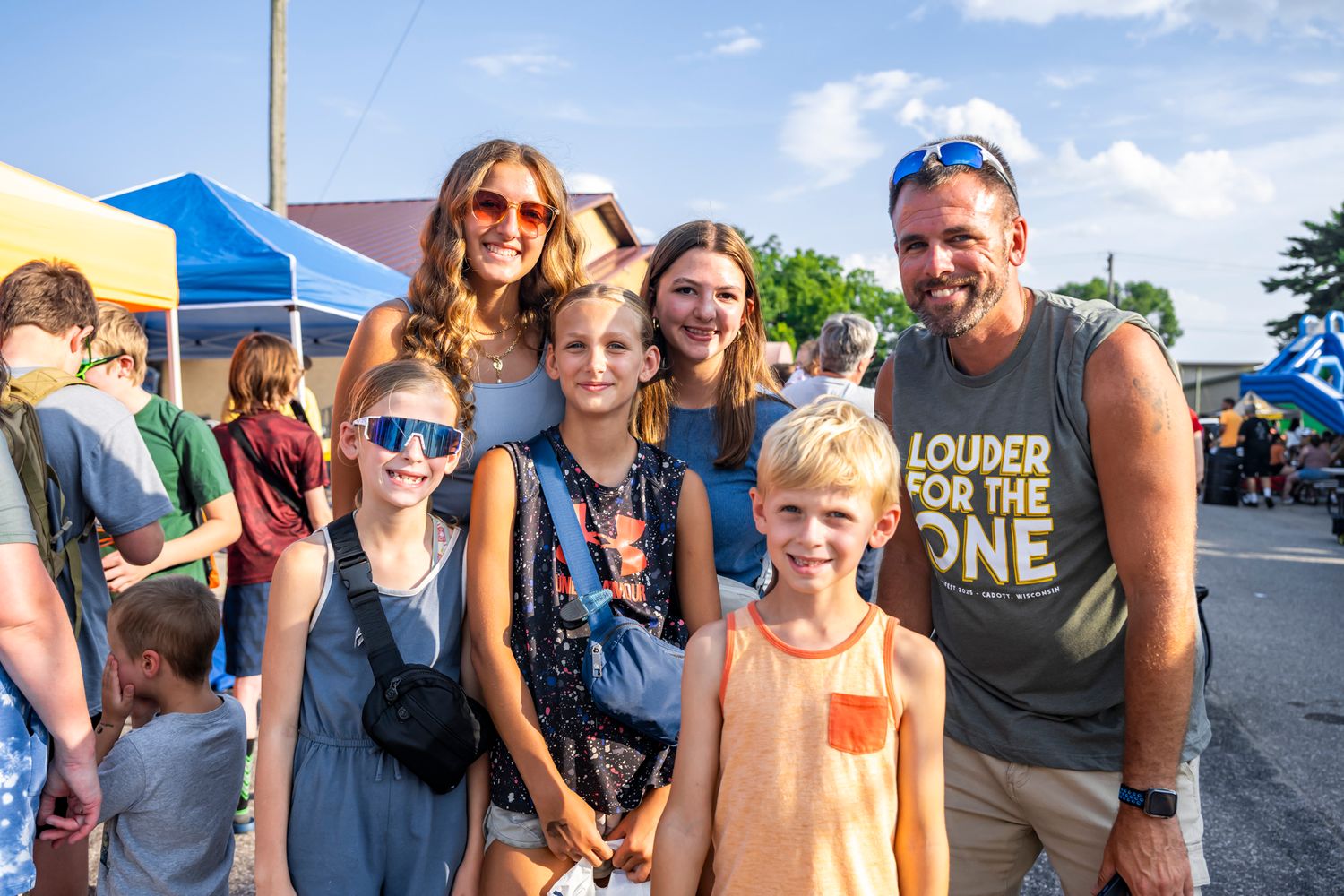 Group of smiling people gathered together at an outdoor summer festival.