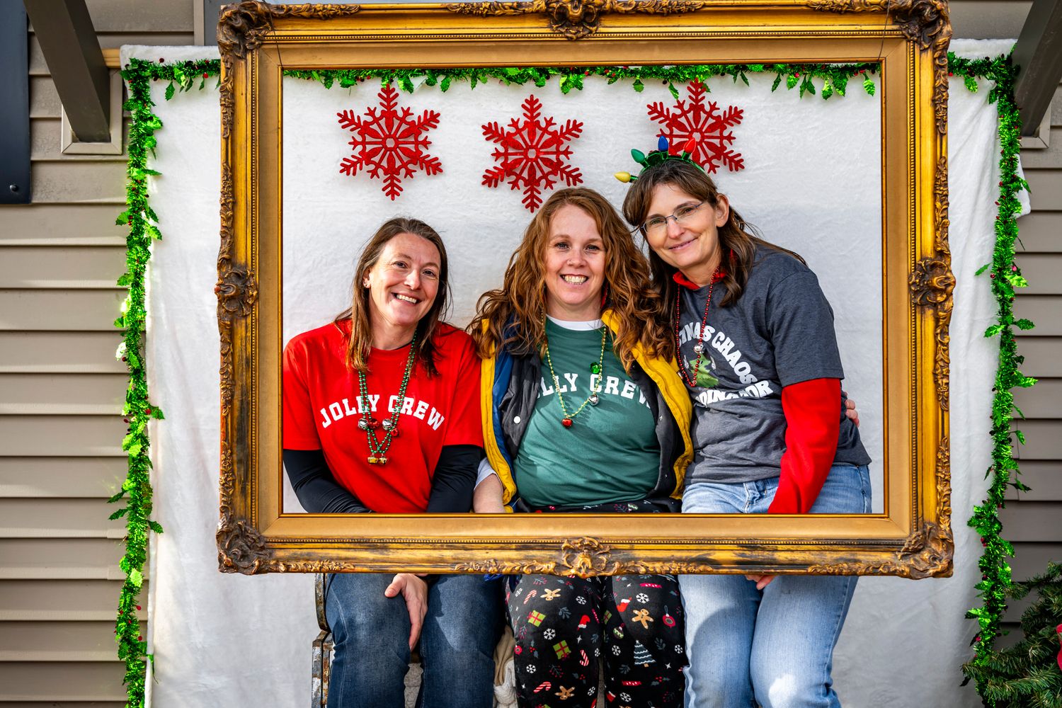 Holiday-themed photo setup with gold frame and festive greenery decorations along a wall.