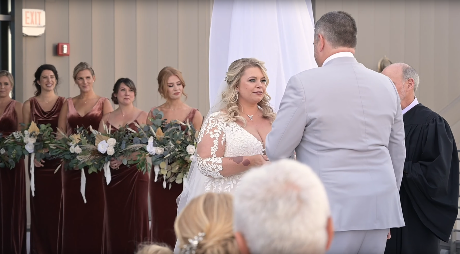 Wedding ceremony guests seated in rows of white chairs inside an elegant indoor venue.