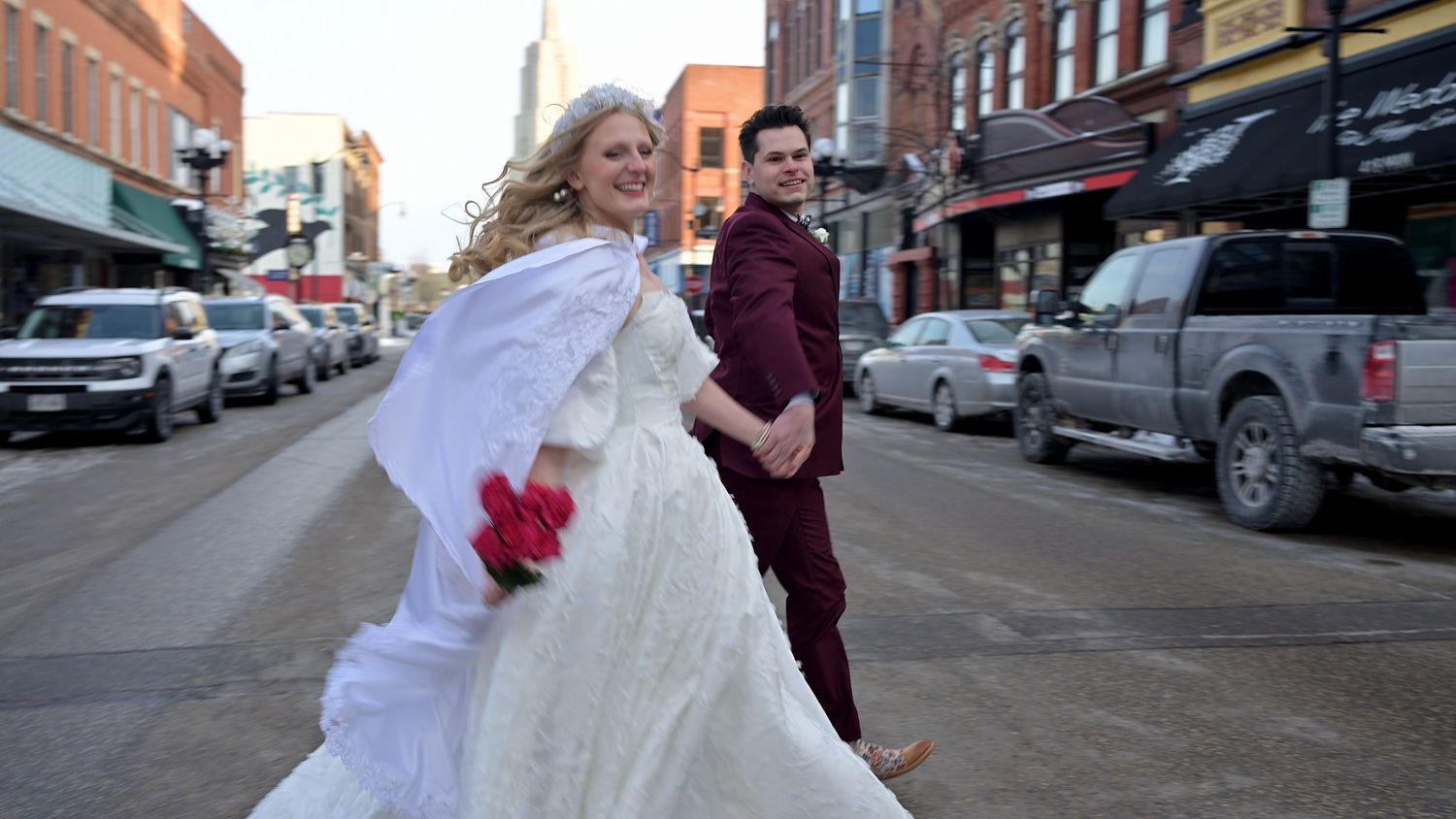 A couple dancing on a city street with the bride's dress flowing in the wind.