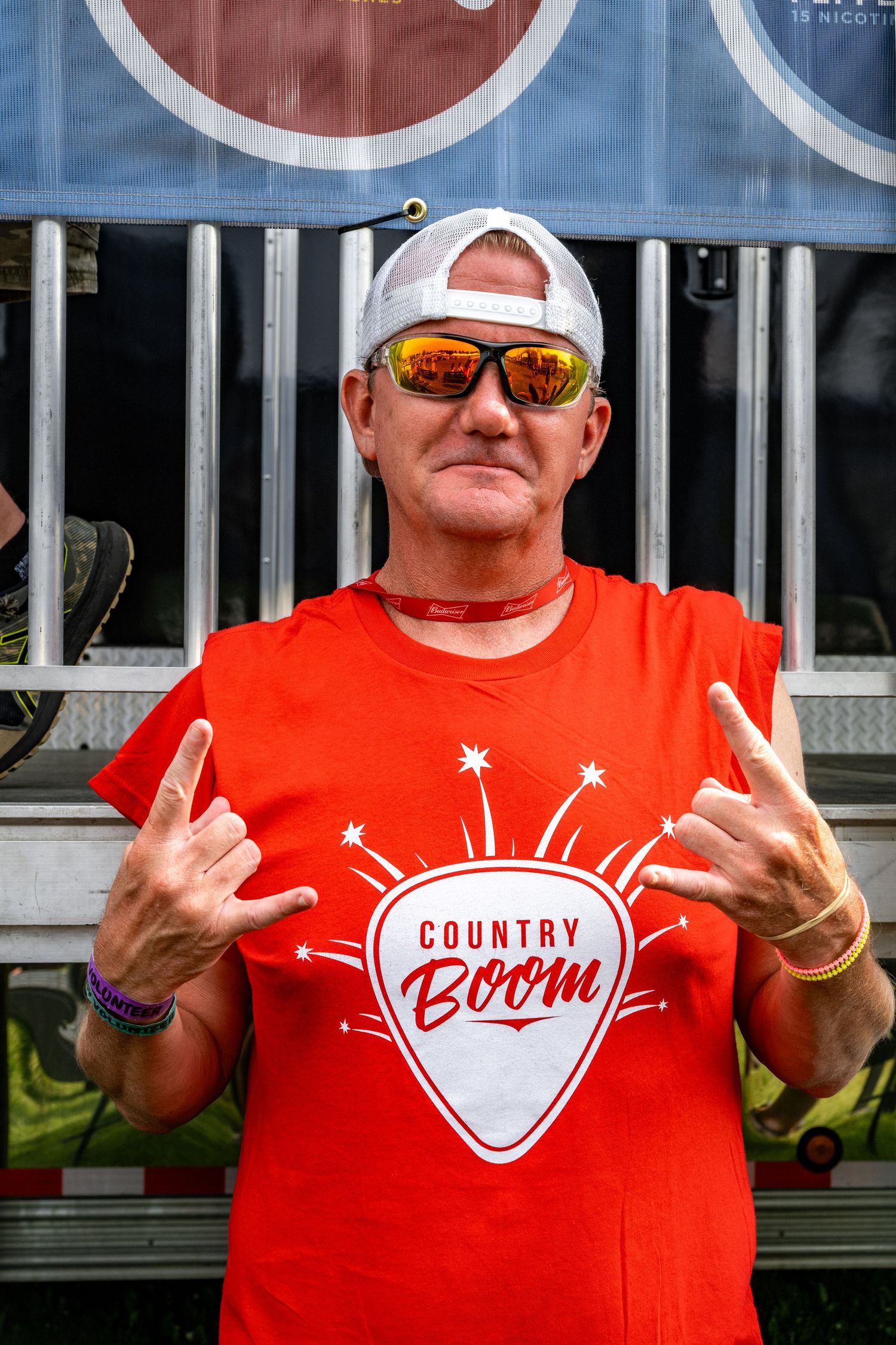 Festival attendees in matching red t-shirts making rock gestures at an outdoor event.