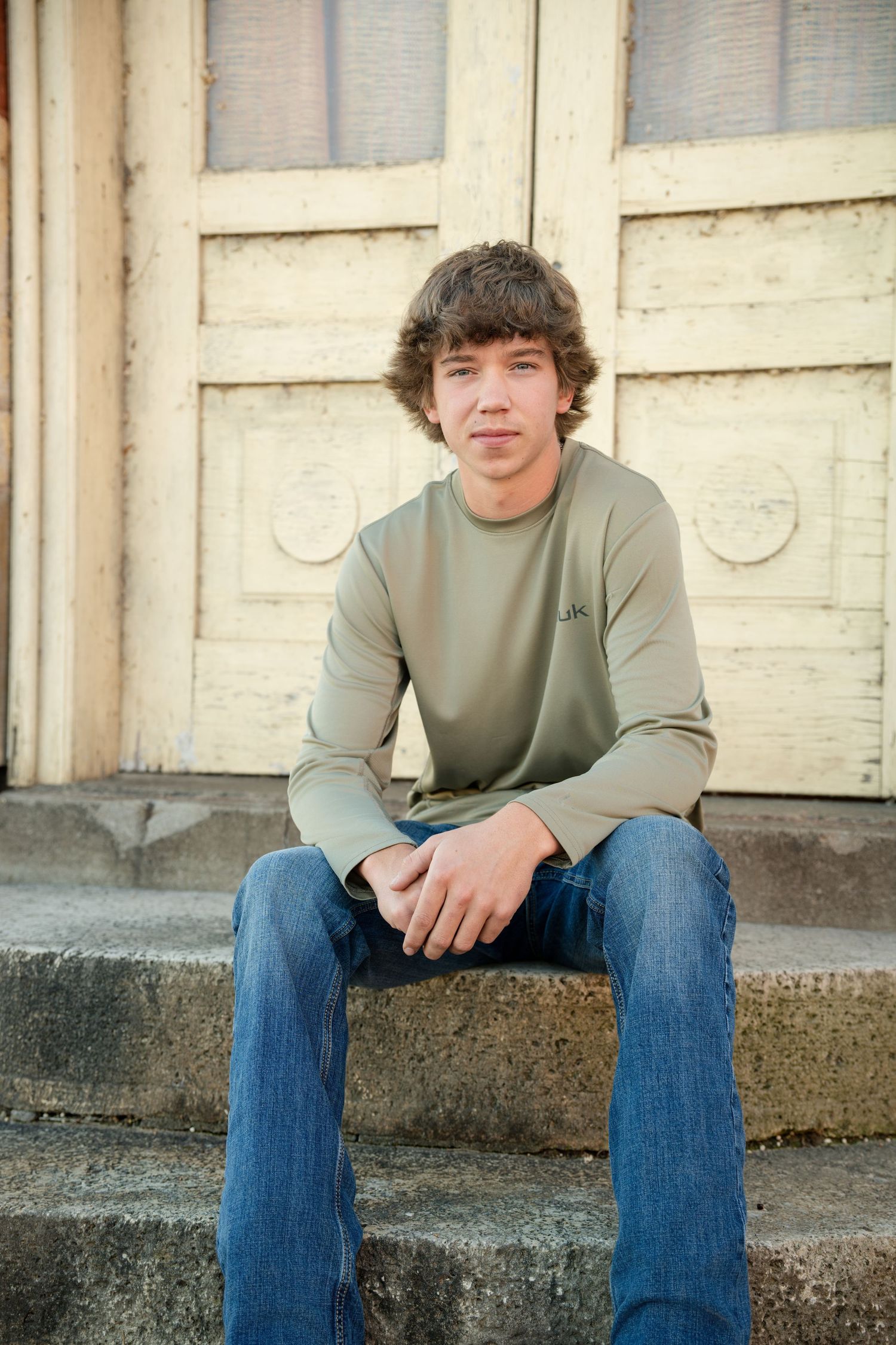 A casual portrait series taken outdoors against a textured wall background.