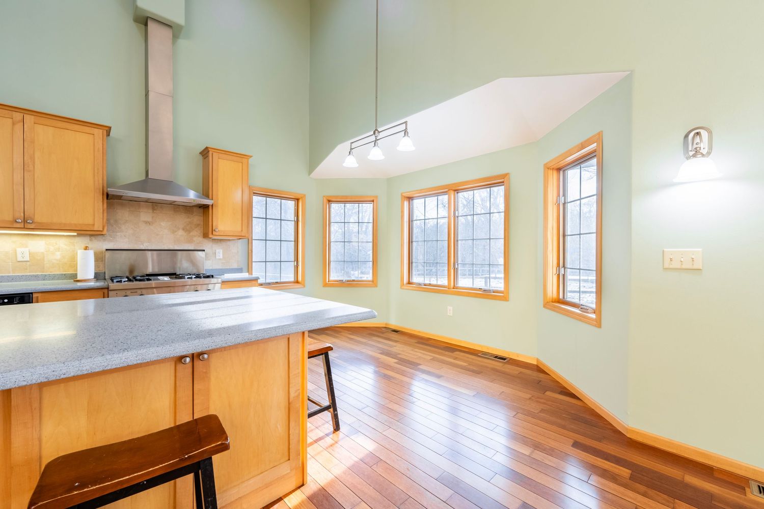 Modern kitchen with light wood cabinets, stainless appliances, and vaulted ceiling with natural lighting.