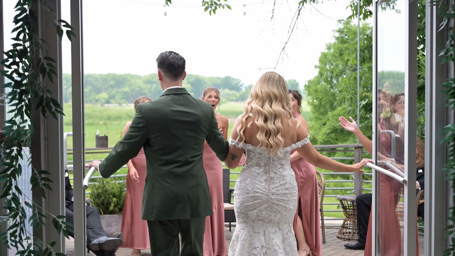 Wedding party walking across a rustic wooden bridge surrounded by greenery.