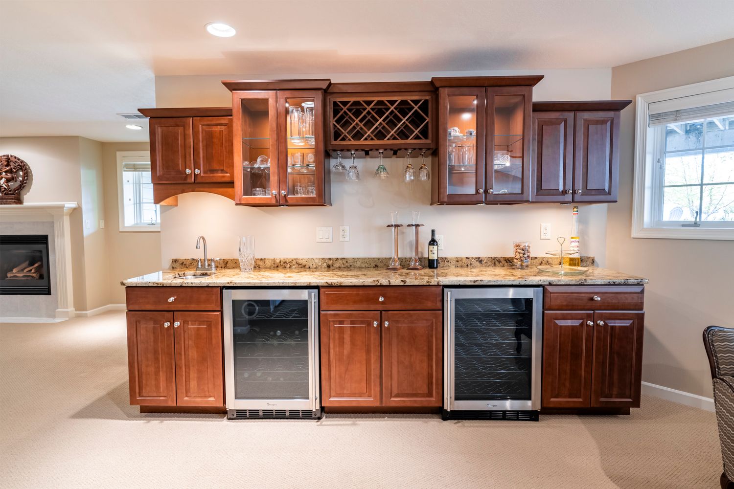 Basement bar area featuring rich wood cabinets, wine storage, and multiple beverage fridges.