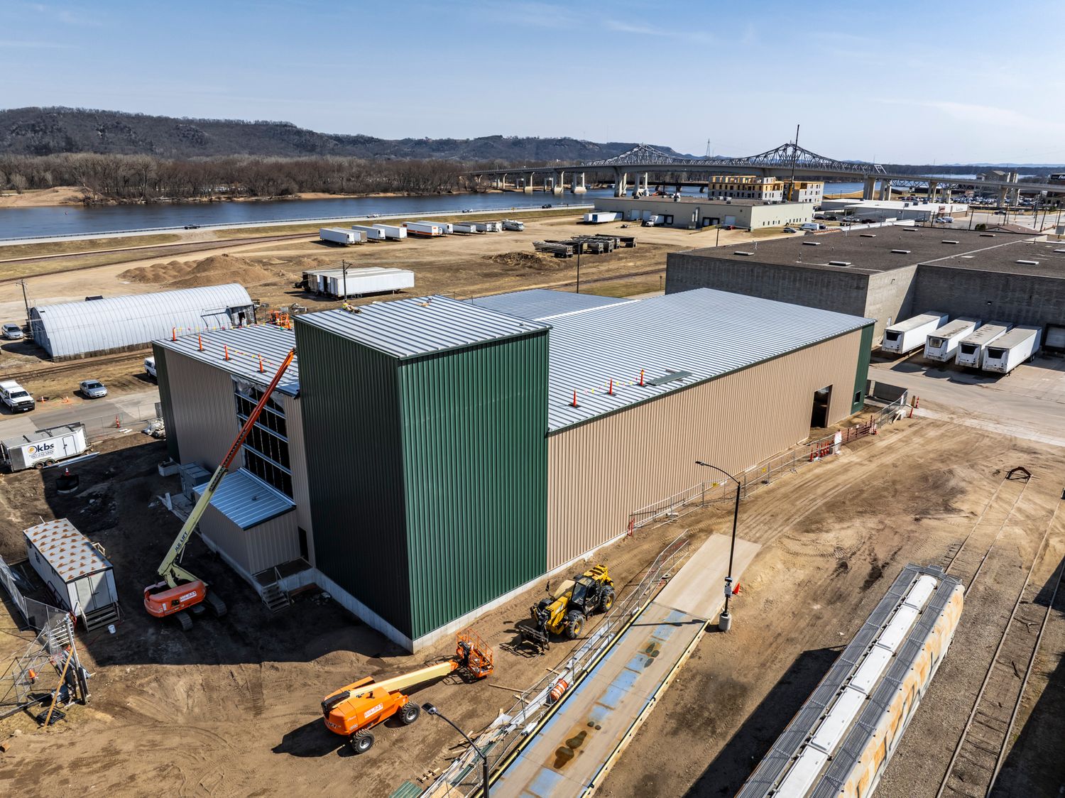 Industrial facility expansion showing new green metal building construction.