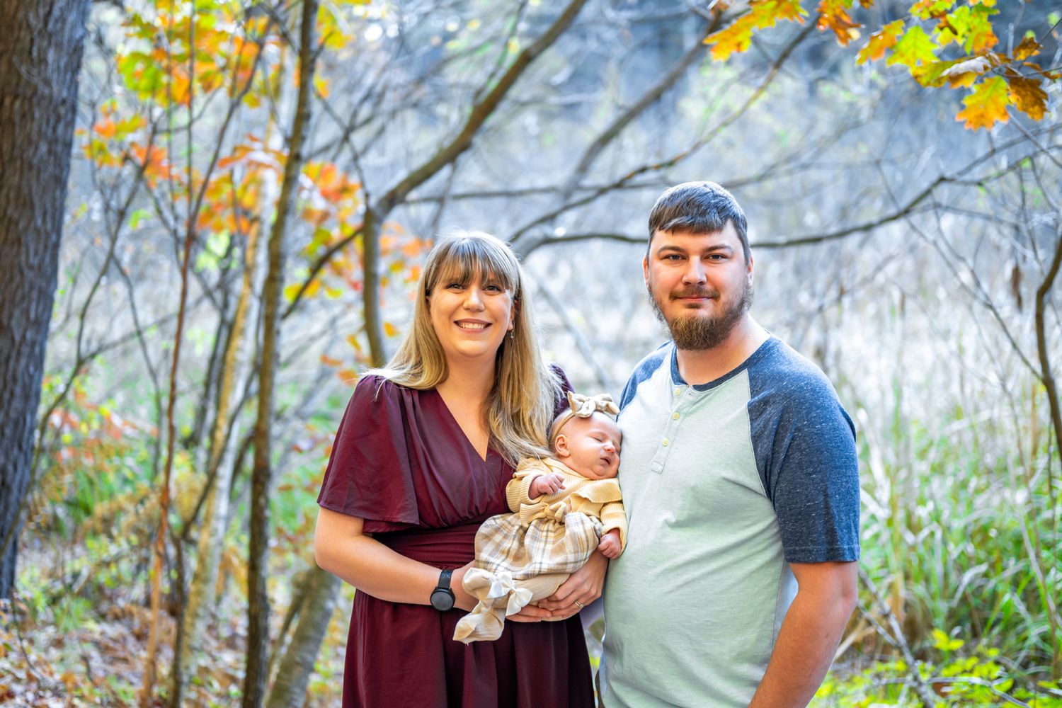 Family portrait session in a scenic autumn forest with golden leaves and natural lighting.