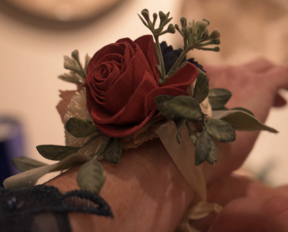 Close-up details of burgundy rose boutonnieres and floral arrangements.